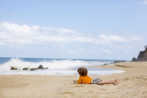 Caucasian boy laying on beach