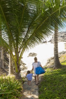 Caucasian mother and sun descending staircase to beach