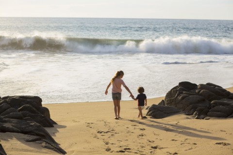 Caucasian brother and sister holding hands on beach