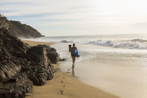 Caucasian mother carrying son on beach