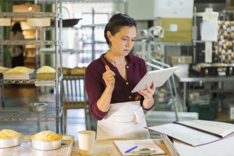 Caucasian woman using digital tablet in bakery