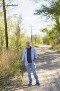 Caucasian man standing on dirt road holding stick