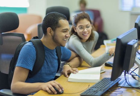 Mixed Race boy and girl using computer in library