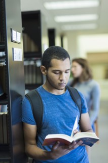Mixed Race boy reading book in library