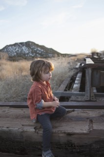 Caucasian boy sitting on wood outdoors