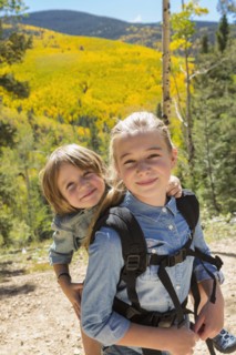 Caucasian girl carrying brother on back