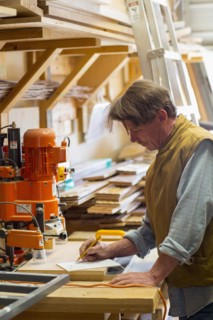 Caucasian carpenter writing on notepad in workshop