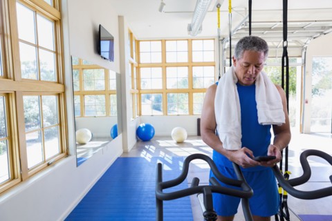 Mixed Race man texting on cell phone in gymnasium
