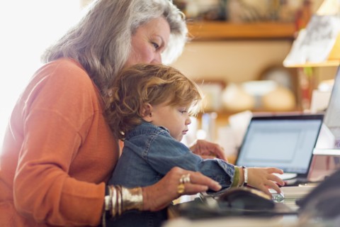 Caucasian baby boy in lap of grandmother using computer