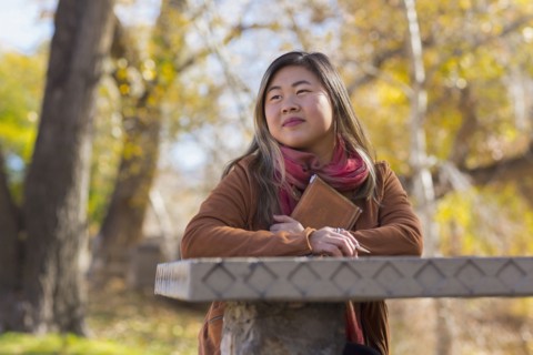 Asian woman holding journal at table in autumn