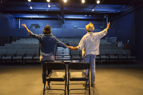 Caucasian actors rehearsing waving in theater