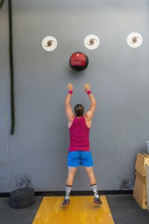 Mixed Race man throwing heavy ball against wall