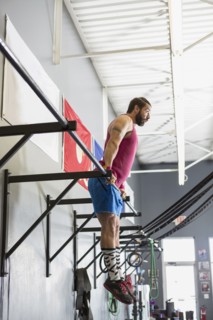Mixed Race man working out on bars in gymnasium