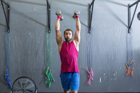 Mixed Race man lifting dumbbells in gymnasium