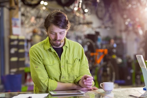 Caucasian worker using digital tablet in bicycle shop