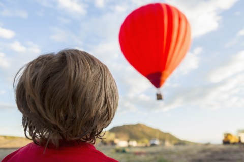 Caucasian boy watching distant hot air balloon