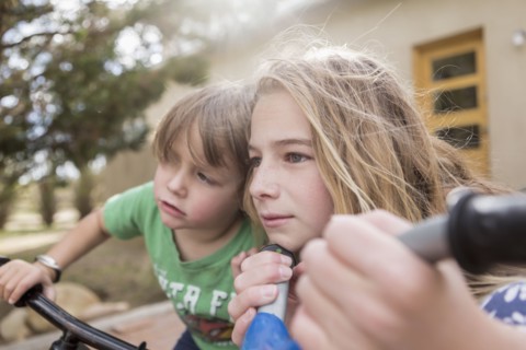 Wind blowing hair of Caucasian boy and girl on bicycles