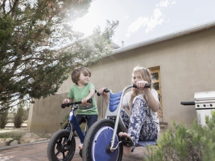 Caucasian boy and girl riding bicycles near house