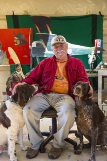 Portrait of older Caucasian man sitting in workshop with dogs