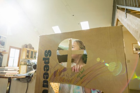 Caucasian girl playing in cardboard house