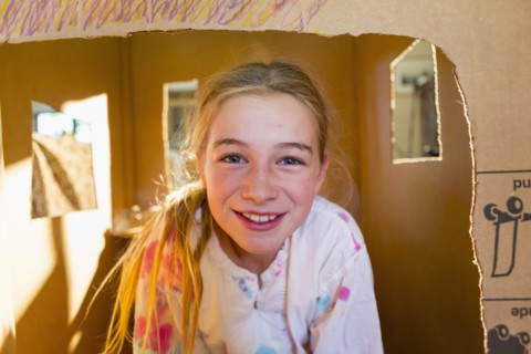Caucasian girl playing in cardboard house