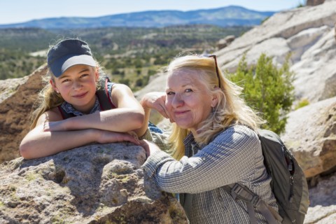 Portrait of Caucasian grandmother and granddaughter leaning on rock