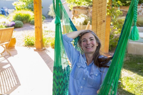 Older Caucasian woman laying in green hammock