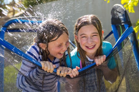 Water splashing on Caucasian girls leaning on netting