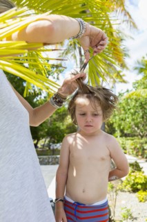 Caucasian mother cutting hair of son outdoors