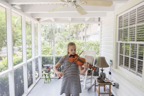 Caucasian girl playing violin on patio