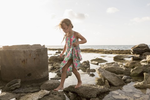 Caucasian girl walking on rocks at beach