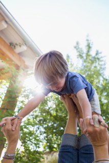 Caucasian boy balancing on feet of mother