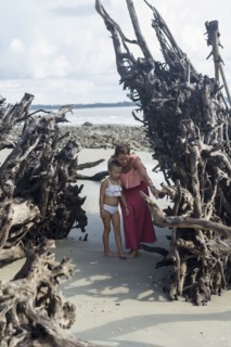 Caucasian mother and daughter examining driftwood on beach