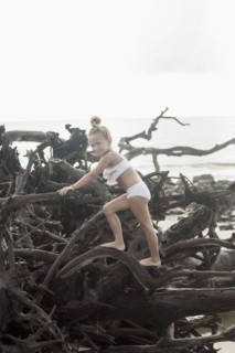 Caucasian girl climbing on driftwood at beach