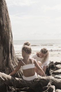 Caucasian girl sitting on driftwood at beach