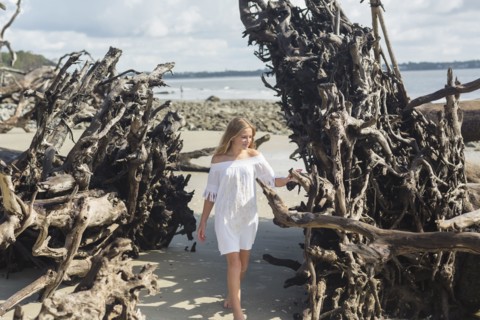 Caucasian girl admiring driftwood on beach