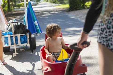 Caucasian boy riding in red wagon