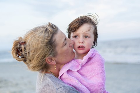 Caucasian mother holding son at beach