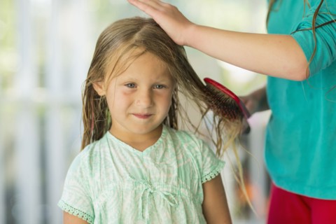 Caucasian girl brushing wet hair of sister