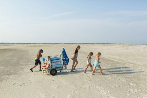 Caucasian boy and girls pulling cart on beach