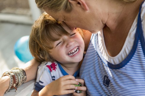 Caucasian mother hugging laughing son holding toy car