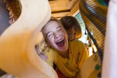 Caucasian brother and sister laughing under table