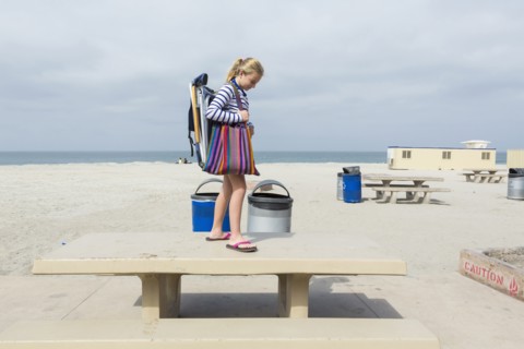 Caucasian girl standing on picnic table at beach