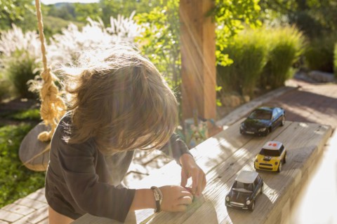 Sunshine on a Caucasian boy playing with toy cars