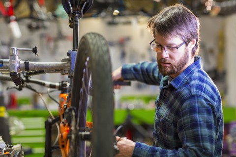 Caucasian man repairing bicycle in shop