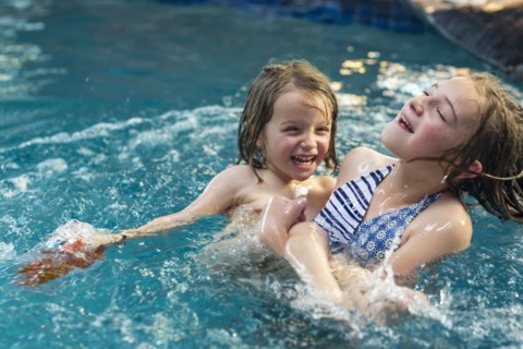 Caucasian brother and sister playing in swimming pool