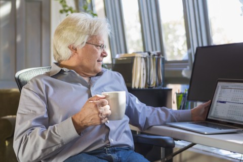 Caucasian man drinking coffee and using laptop