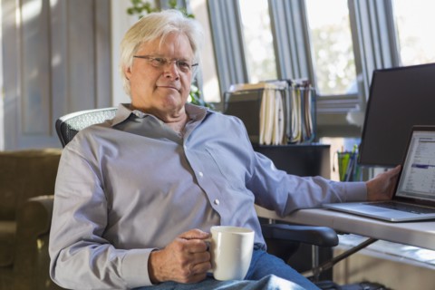 Caucasian man drinking coffee and using laptop