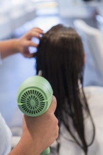 Caucasian stylist drying hair of woman