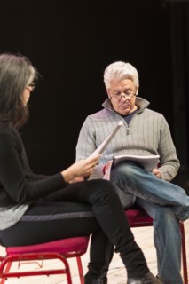 Hispanic man and woman reading scripts on theater stage